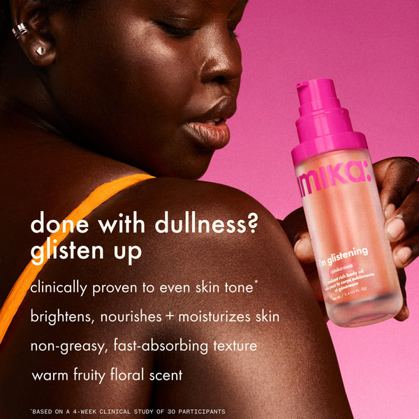 a person smiles while holding a bottle of i’m glistening body oil against a pink background, showing radiant skin on the shoulder. text reads “done with dullness? glisten up” and lists clinically proven tone-evening, brightening, moisturizing benefits, a fast-absorbing texture, and a warm fruity floral scent.
