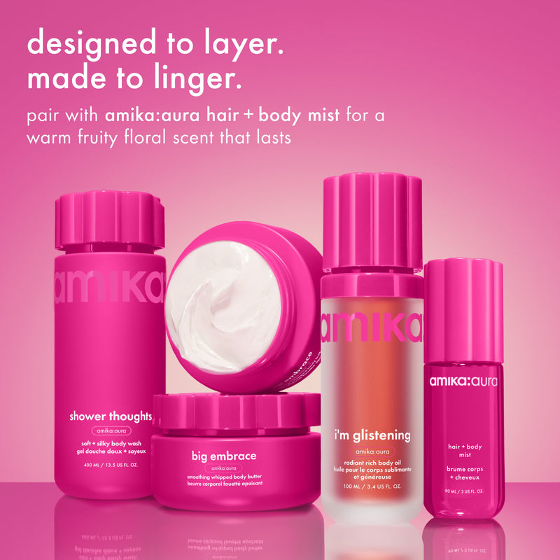 amika's body wash, body cream, and aura hair and body mist are grouped together on a pink background. text reads “designed to layer. made to linger,” with a note about pairing for a warm fruity floral scent.